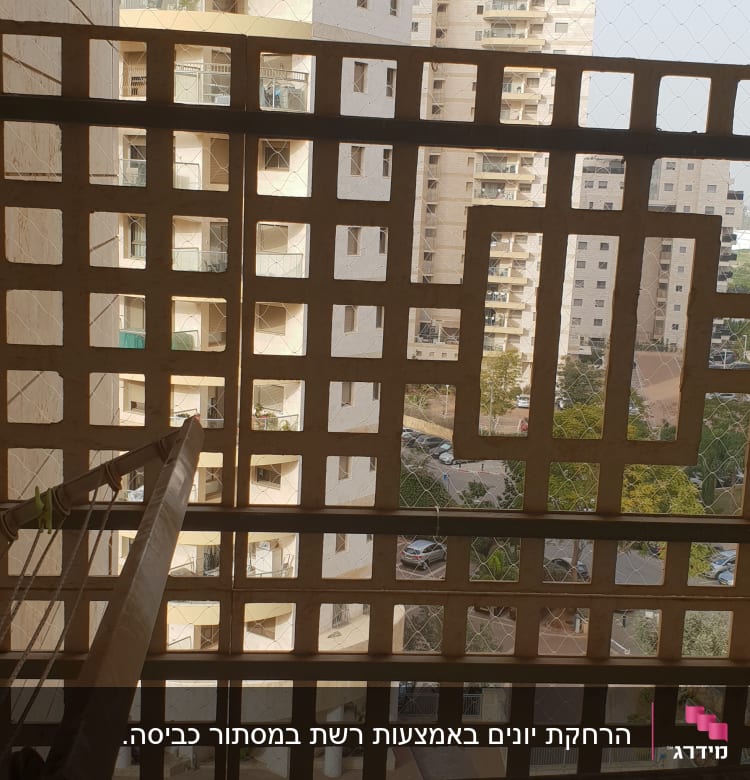 רשת יונים מותקנת על מרפסת עם בניינים ברקע